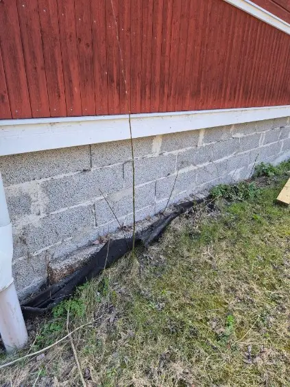 Grundmur i lättbetong med skadad fuktisolering vid husets fasad